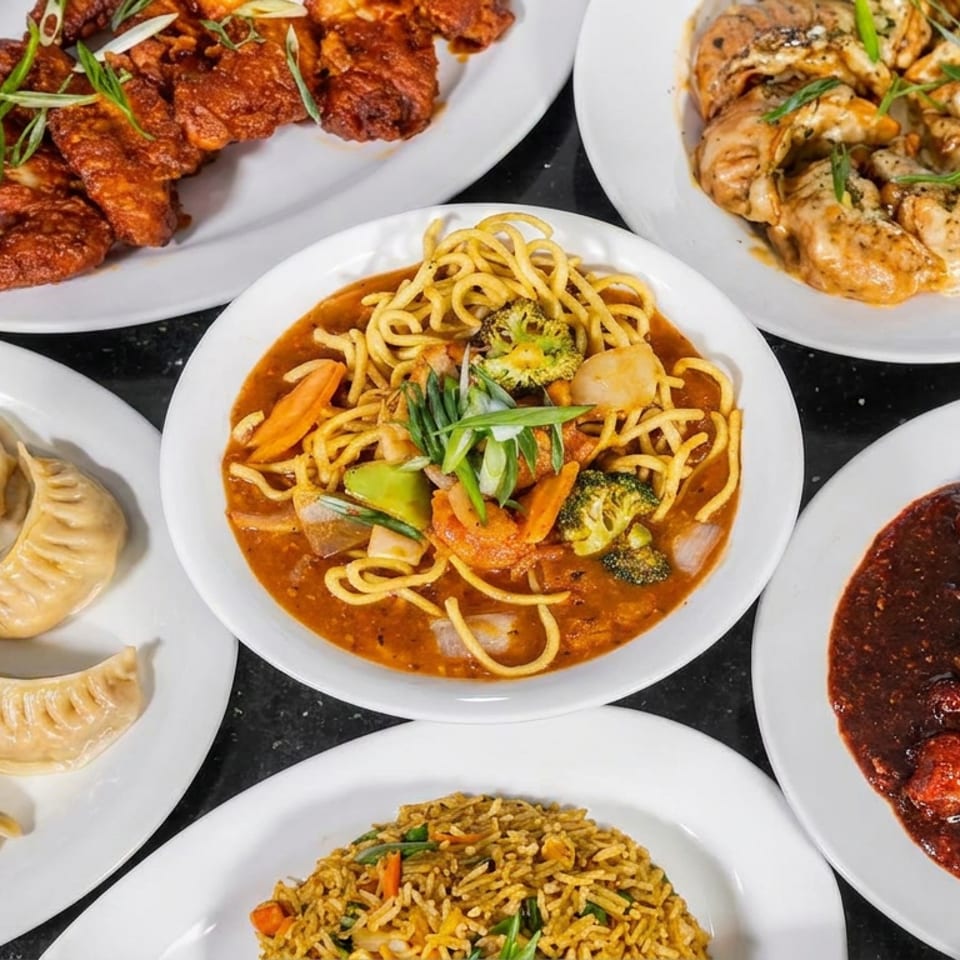 Assorted Asian dishes arranged on white plates, including dumplings, noodles, fried appetizers, saucy entrée, shrimp, and fried rice.